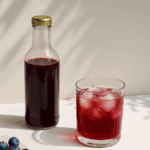 photo de mise en scène avec bouteille contenant un cordial de myrtilles maison idéal pour les cocktails studio aurelia cordiez